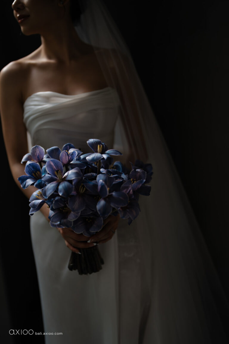 Bride holding a bouquet of deep blue orchids in a fitted white gown, Bali, Axioo Bali