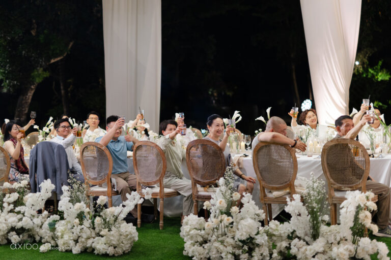 Guests raising their glasses at a long garden reception table, Bali, Axioo Bali