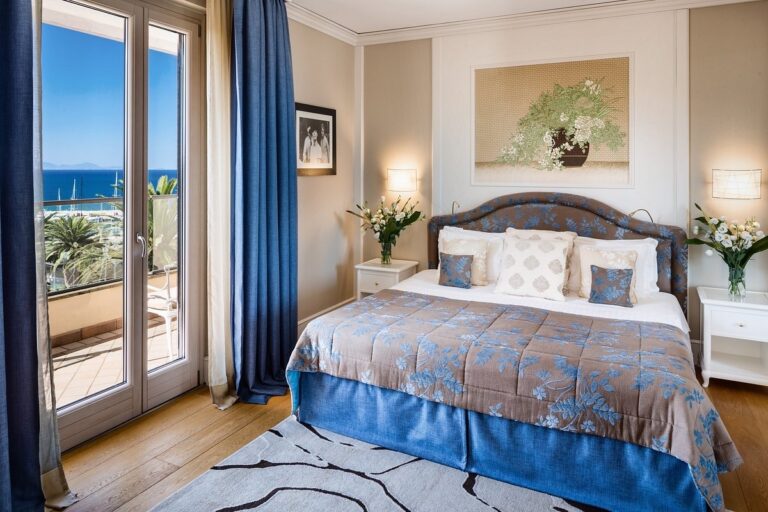 A sea-view bedroom in soft stripes, a balcony opening to the marina, Baglioni Resort Cala del Porto