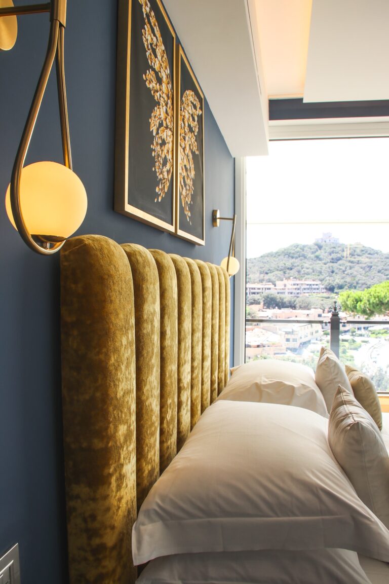 A suite with a gold velvet headboard and a view over the marina, Baglioni Resort Cala del Porto