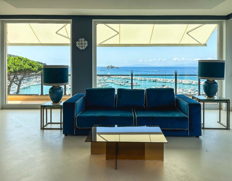 A suite sitting room with a blue velvet sofa and panoramic sea views, Baglioni Resort Cala del Porto