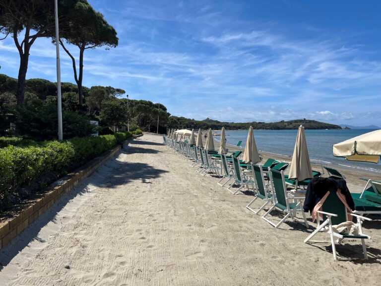 The private beach, green parasols and loungers along the sand, Baglioni Resort Cala del Porto