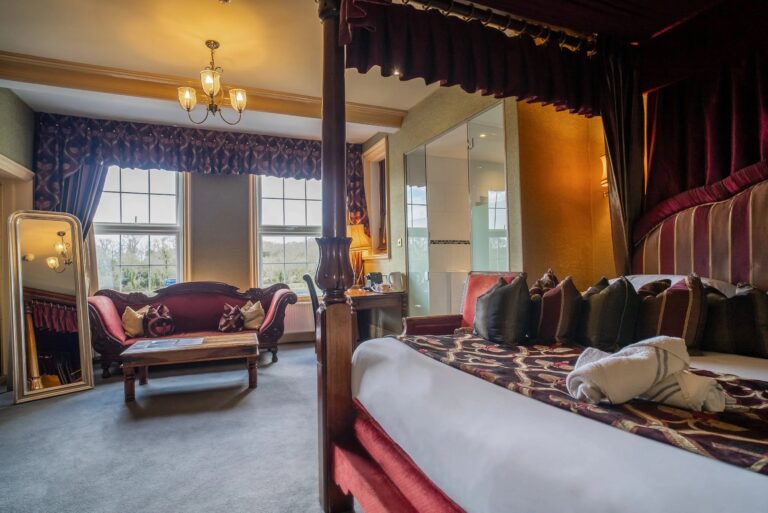 A bedroom with a draped four-poster bed and a sofa beneath two sash windows, Balmer Lawn Hotel & Spa