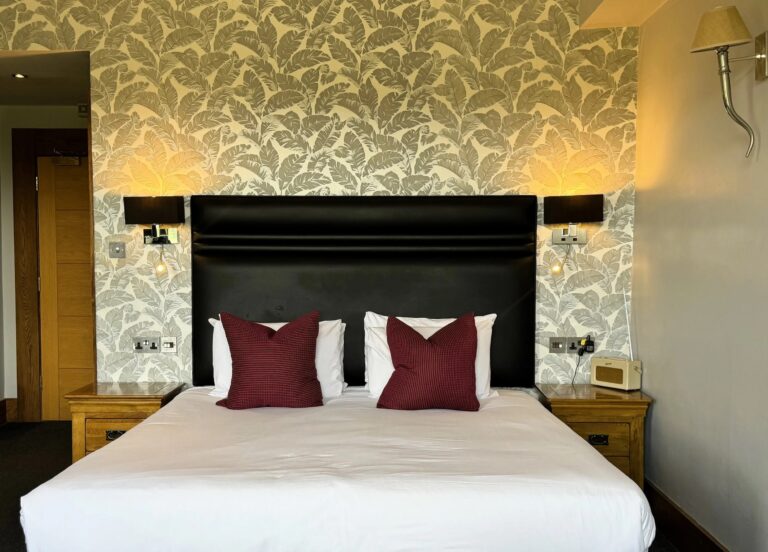 A Superior room with a king-size bed, leaf-pattern wallpaper and red cushions, Balmer Lawn Hotel & Spa