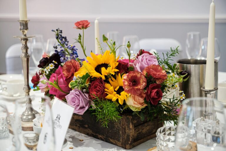 A wooden crate centrepiece of sunflowers, roses and delphiniums between silver candlesticks, Balmer Lawn Hotel & Spa