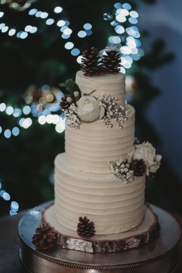 A three-tier buttercream wedding cake decorated with white roses, gypsophila and pine cones, Balmer Lawn Hotel & Spa