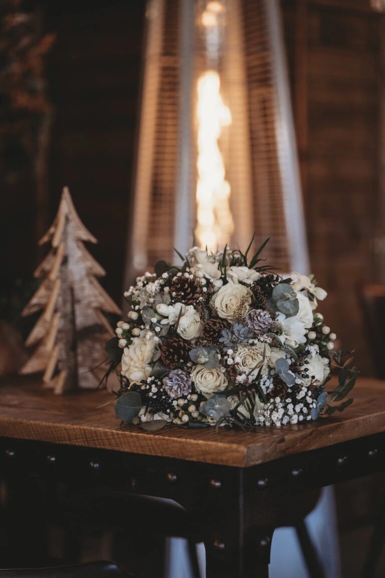 A winter bridal bouquet of cream roses, pine cones and eucalyptus on a wooden table, Balmer Lawn Hotel & Spa