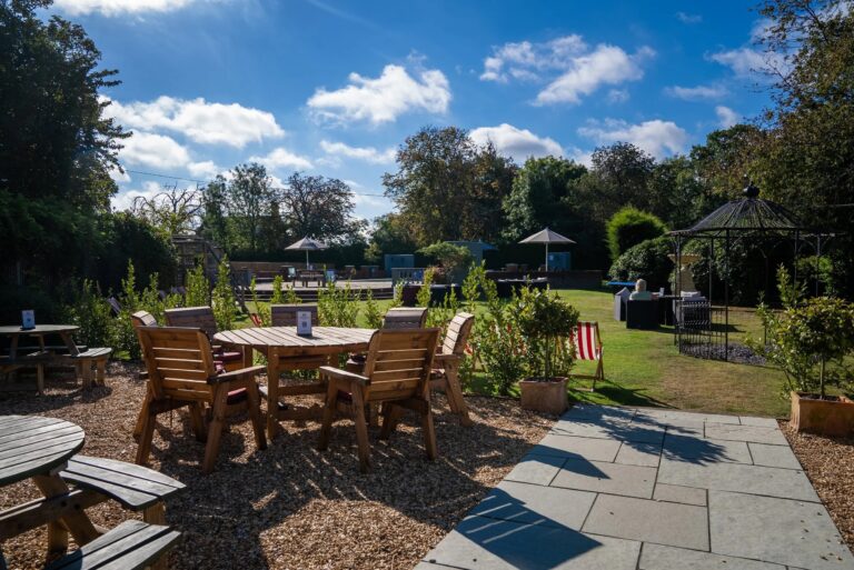 The garden terrace with timber tables and chairs, lawns and a wrought-iron gazebo in the sunshine, Balmer Lawn Hotel & Spa