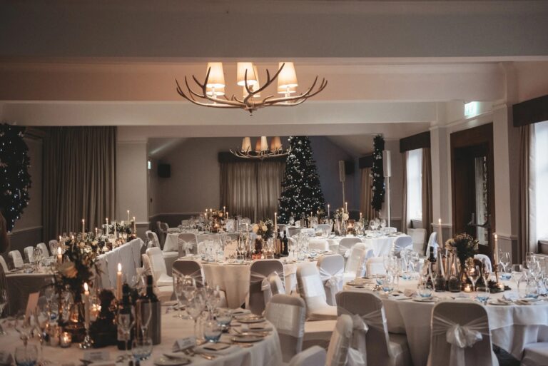 A function room dressed for a Christmas wedding, with candles, greenery and a lit tree at the far end, Balmer Lawn Hotel & Spa