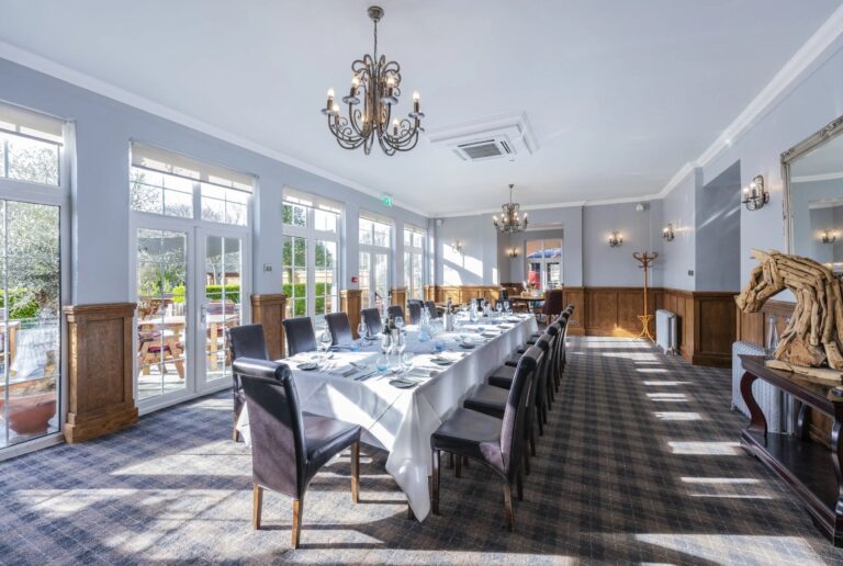 A long banqueting table in the Savernake Room, with wall-to-wall windows onto its terrace, Balmer Lawn Hotel & Spa