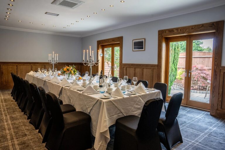 The Avon Room set with a long table, candelabra and flowers, its doors open to a private terrace, Balmer Lawn Hotel & Spa