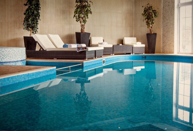 The indoor pool, with loungers, potted trees and a jacuzzi at one end, Balmer Lawn Hotel & Spa