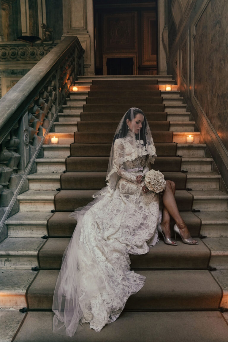 A bride resting on a candlelit stone staircase, Venice, Barbara Zanon Photography