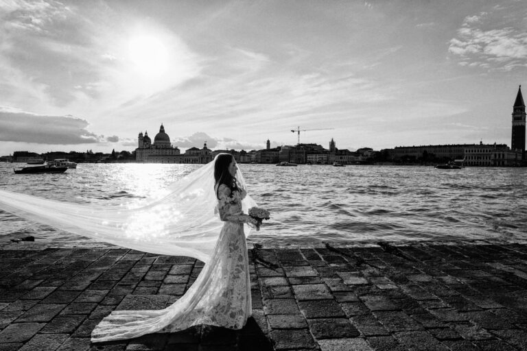 The bride's veil streaming over the waterfront, the Salute across the water, Venice, Barbara Zanon Photography