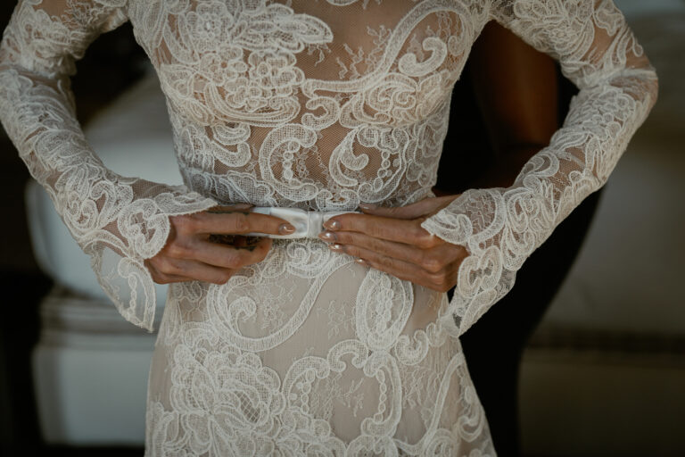 Hands fastening the lace of the wedding dress, Venice, Barbara Zanon Photography