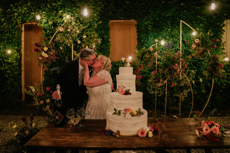 A kiss behind the wedding cake in the lamplit garden, Villa Semenza, Lecco, Barbara Zanon Photography