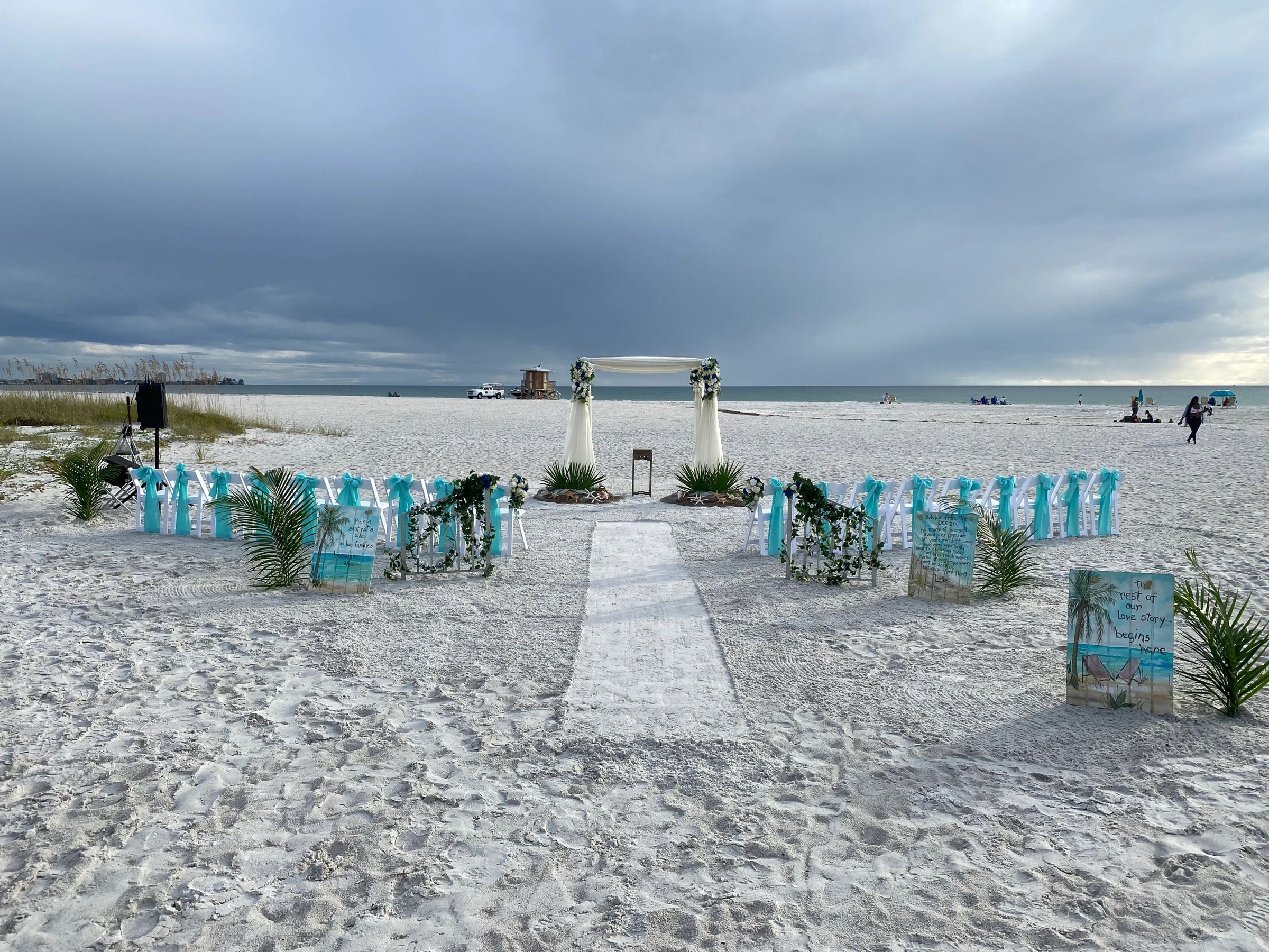 Beach ceremony set-up with turquoise ribbon chairs and a white aisle, Beach Breeze Weddings
