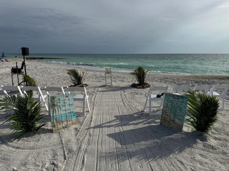 Combed sand aisle lined with palms, white chairs and painted signs by the Gulf, Beach Breeze Weddings