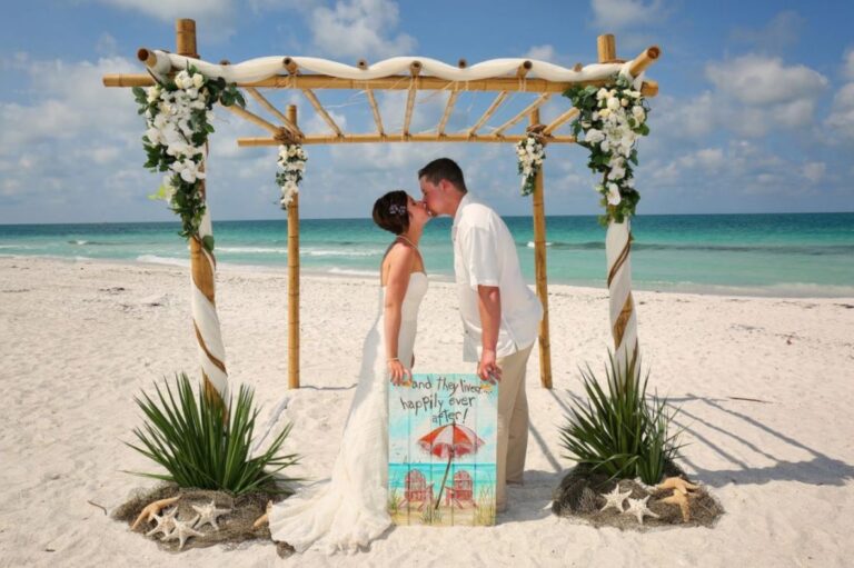 Bamboo arch dressed with white flowers on a white-sand beach, Beach Breeze Weddings