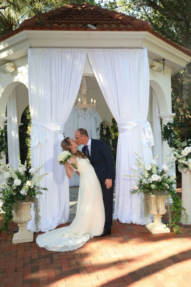Garden gazebo hung with white drapes and white flowers, Beach Breeze Weddings
