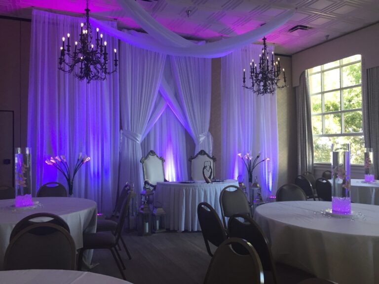 Reception backdrop of white drapery with uplighting and chandeliers, Beach Breeze Weddings