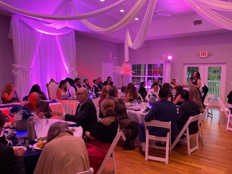Reception dinner beneath a draped ceiling with pink uplighting, Beach Breeze Weddings