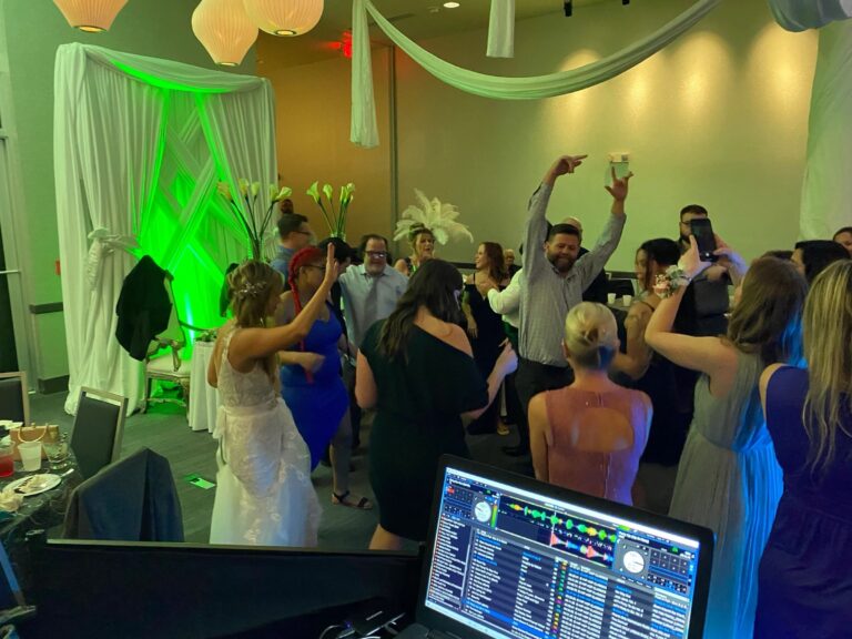 Dance floor beside a draped backdrop with green uplighting, Beach Breeze Weddings