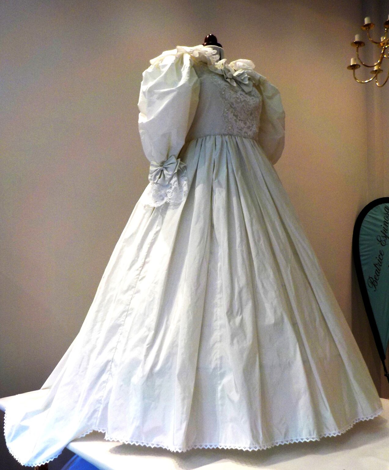 A bespoke ballgown in ivory silk with large puff sleeves and a bow, on a mannequin