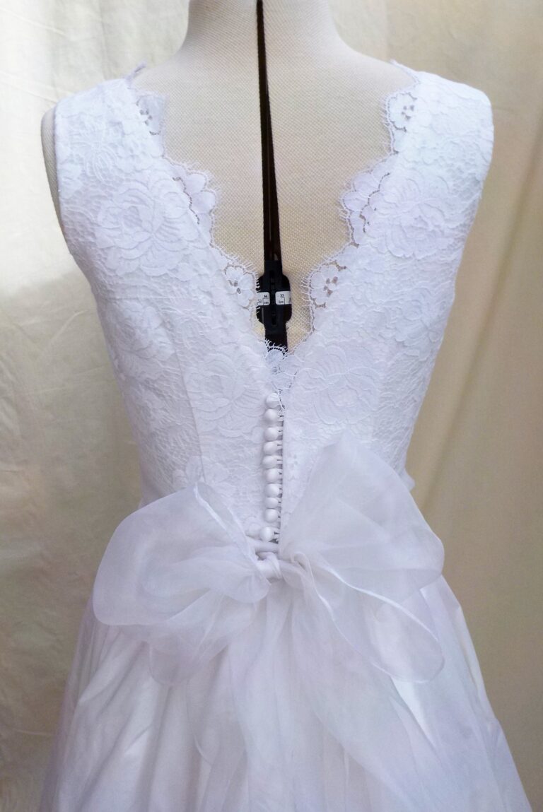 The lace V back of a bridal gown with a row of covered buttons and a tulle bow, Beatrice Espinosa Bridal