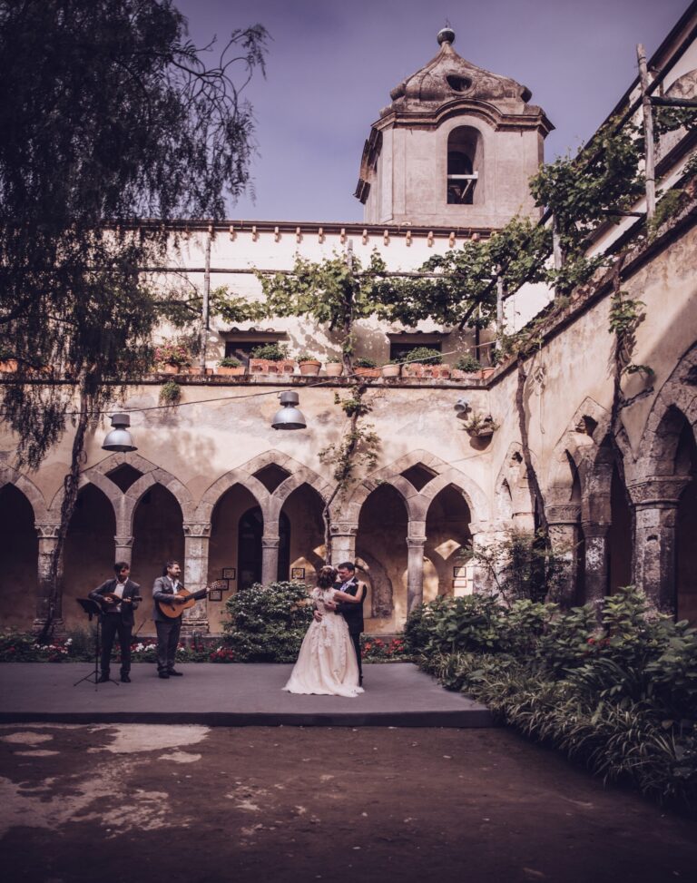 Newlyweds dancing in a stone cloister to two guitarists, Bella Sposa