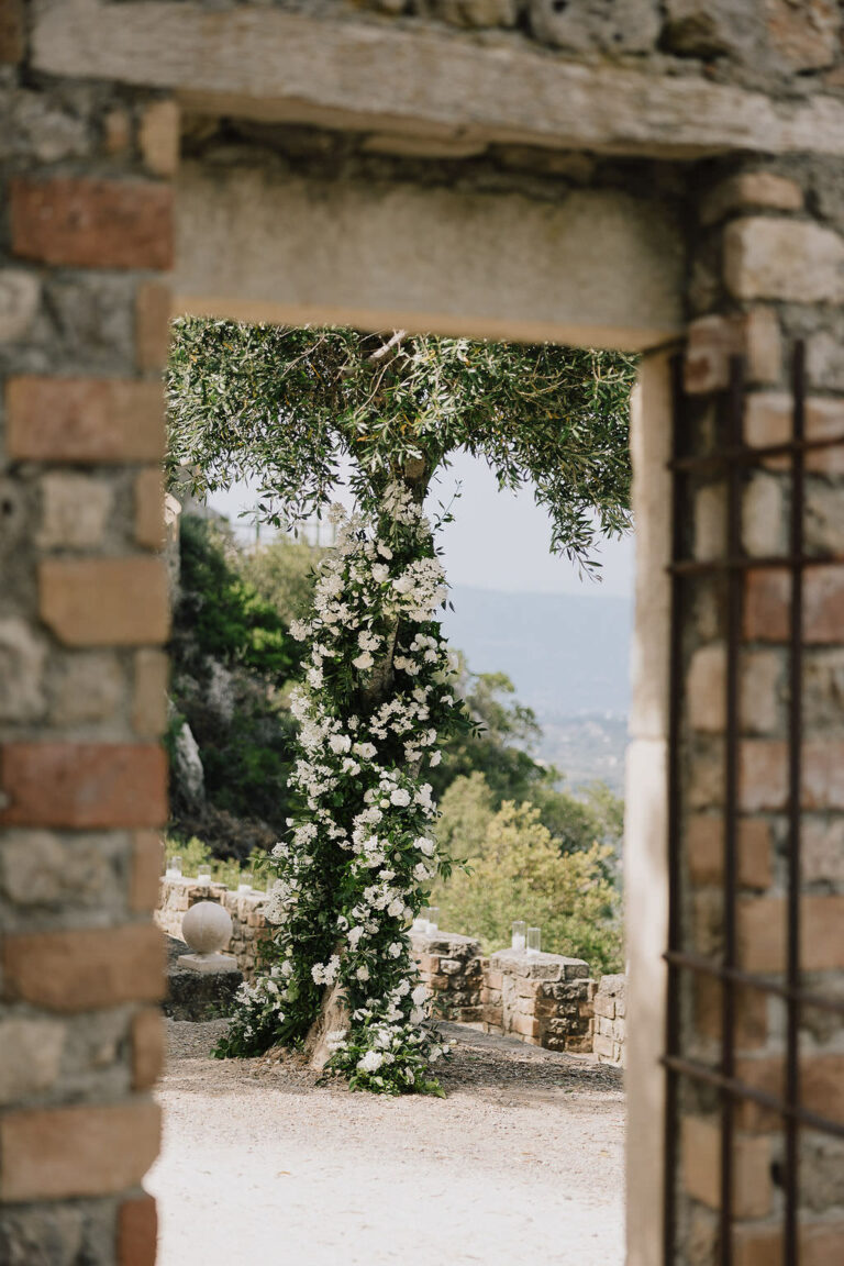 A stone doorway framed in white blooms above the sea in Corfu, Belli Momenti