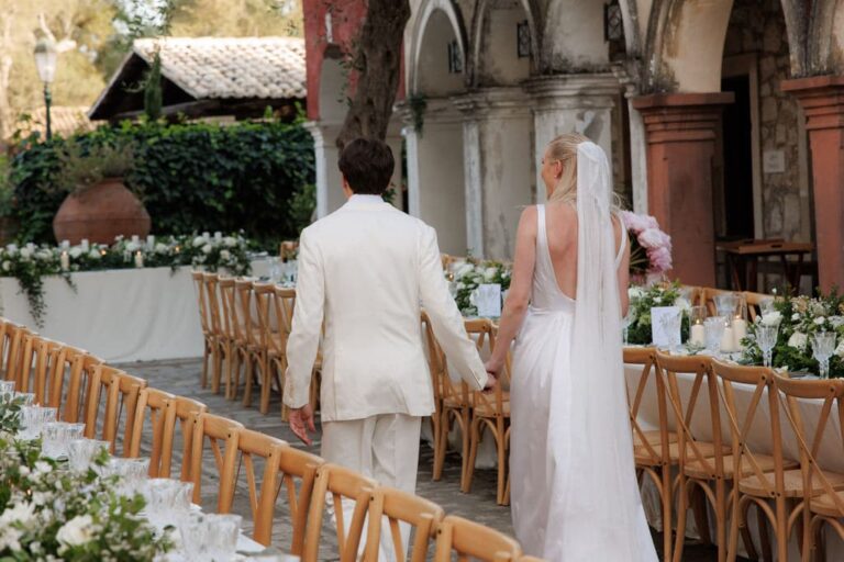 A couple walk beside long banquet tables at Danilia Village, Corfu, Belli Momenti