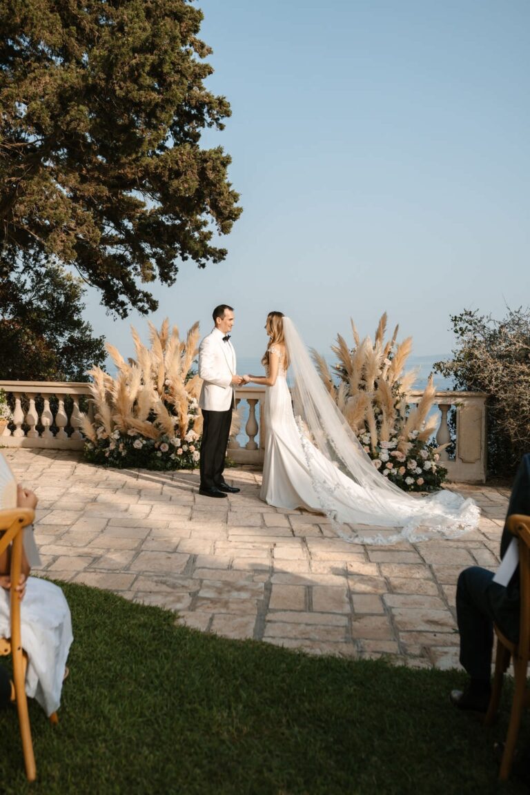 A bride in her veil on a stone terrace beside pampas grass at Villa Sylva, Belli Momenti