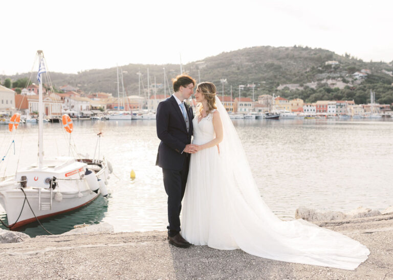 A couple embrace beside moored boats on a Paxos harbour, Belli Momenti