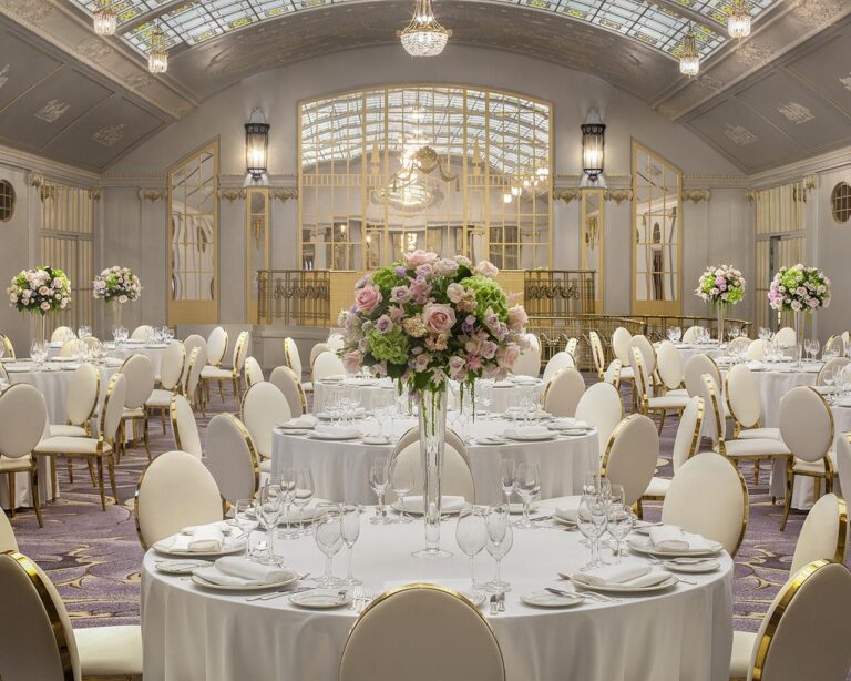 Round tables dressed with tall floral centrepieces in the ballroom, Belmond Grand Hotel Europe