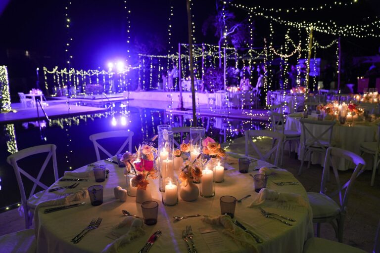 Reception tables with orchids and candles beside a lit pool at night, Better Together Mexico