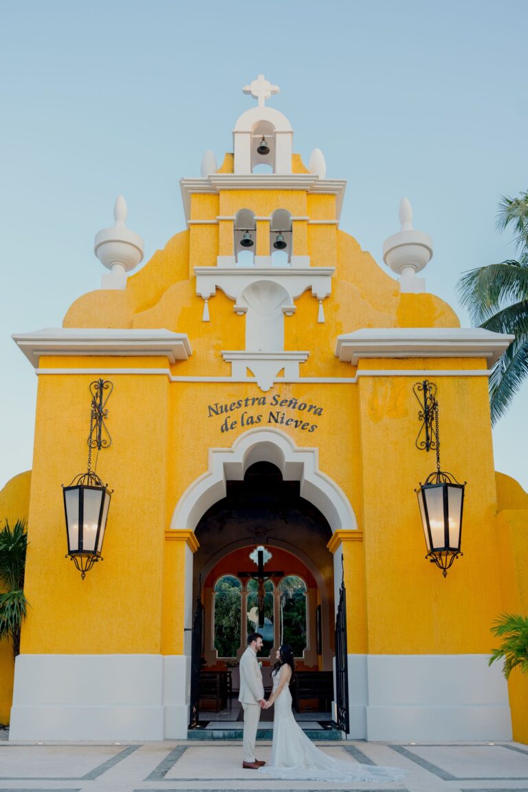 A yellow Mexican chapel used for Catholic weddings, with a couple at the door, Better Together Mexico