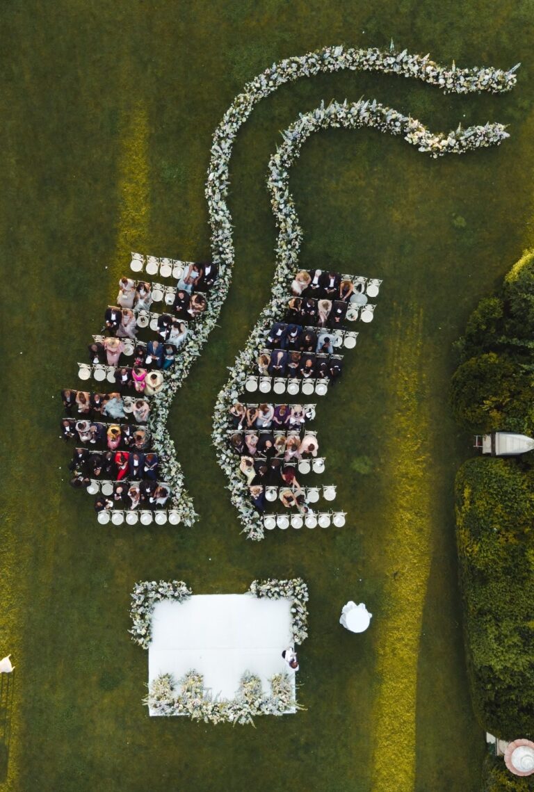 From the air: a serpentine flower-lined table beside the ceremony square, Bianco Bouquet Weddings and Events