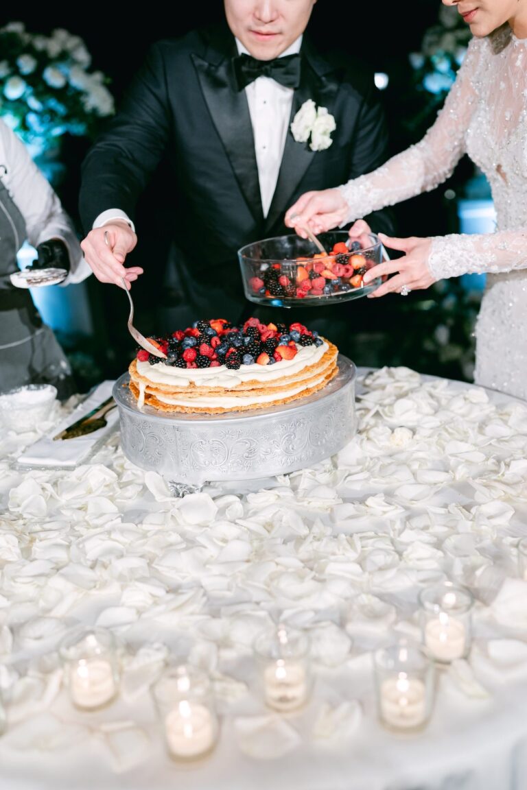 The cake cut over a cloth of white petals and candles, Bianco Bouquet Weddings and Events