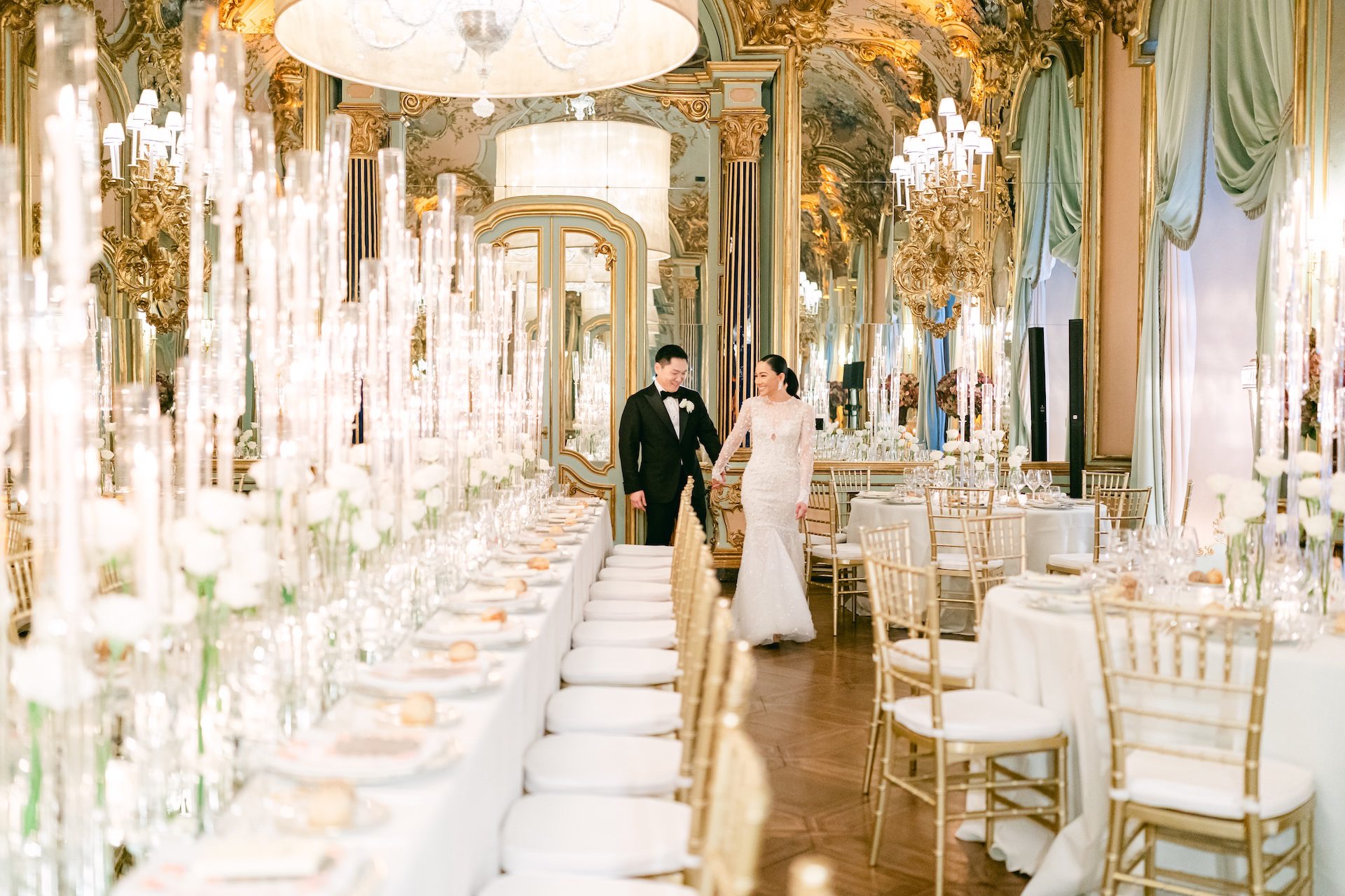 The couple walking a gilt and crystal gallery, the table set in white and gold, Bianco Bouquet Weddings and Events