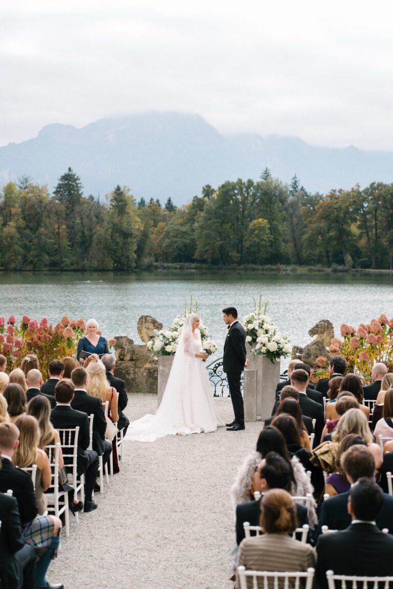 Large lakeside ceremony with guests seated along the aisle, Bilingual Celebrant in Europe