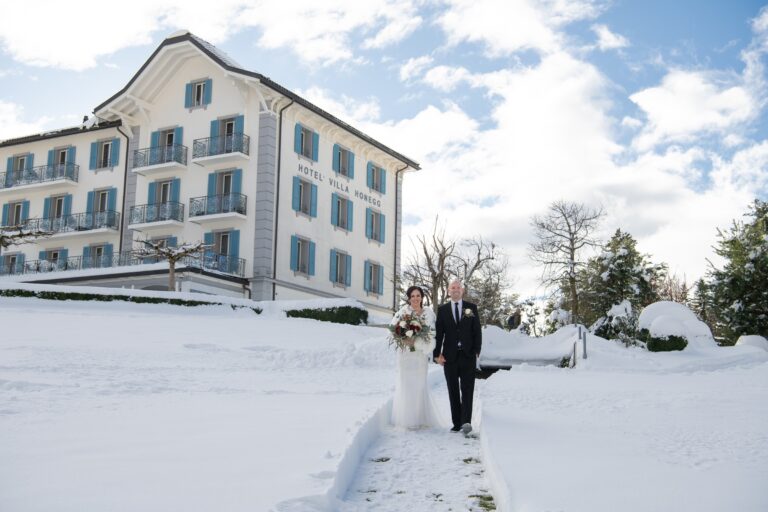 Couple walking through the snow towards Hotel Villa Honegg, Bilingual Celebrant in Europe