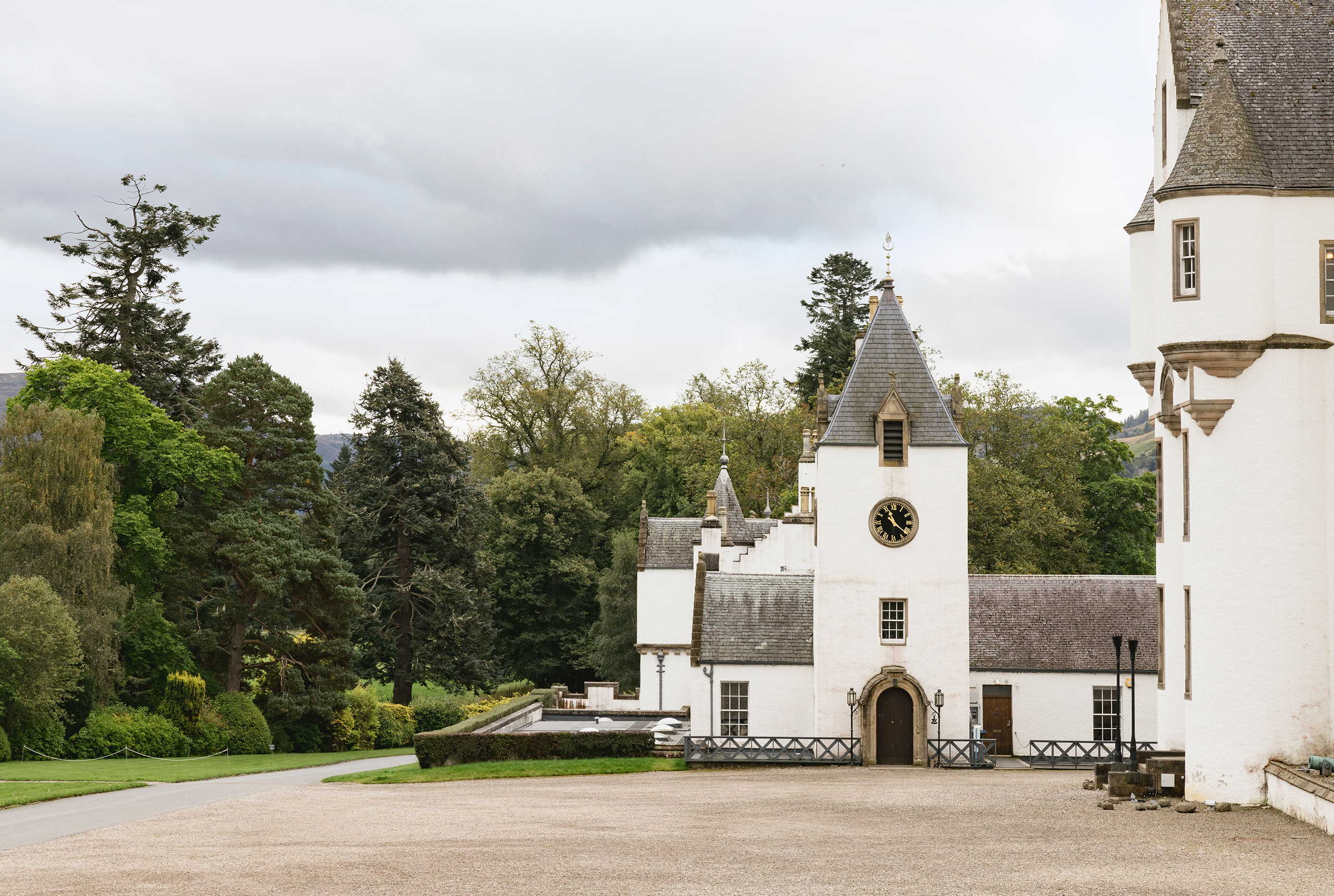 The gravel forecourt and the clock tower wing, with mature trees behind, Blair Castle