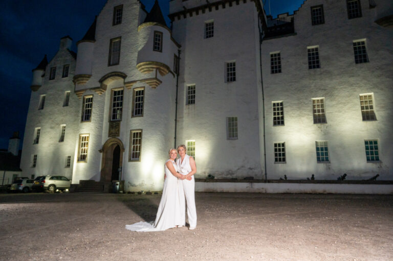 The castle front floodlit at night, with a couple on the forecourt, Blair Castle