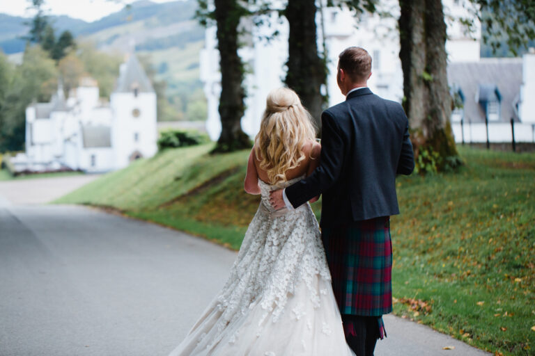 A couple walking down the drive with the castle and hills in the distance, Blair Castle