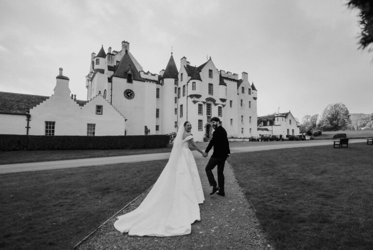 A couple crossing the lawn in front of the castle, in black and white, Blair Castle