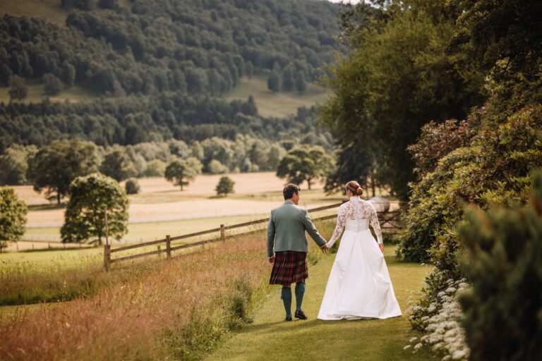 A couple walking through parkland with views over the Atholl hills, Blair Castle