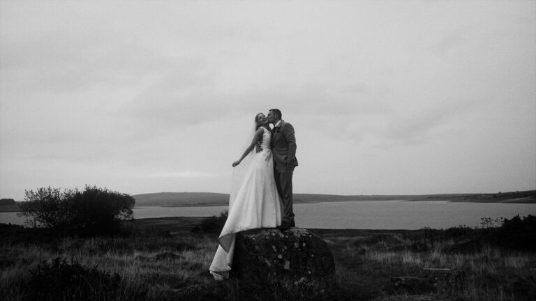 Agnes and Alan on a rock above the water in Cornwall, from their Trevenna Farm wedding film, Blue Ridge Films