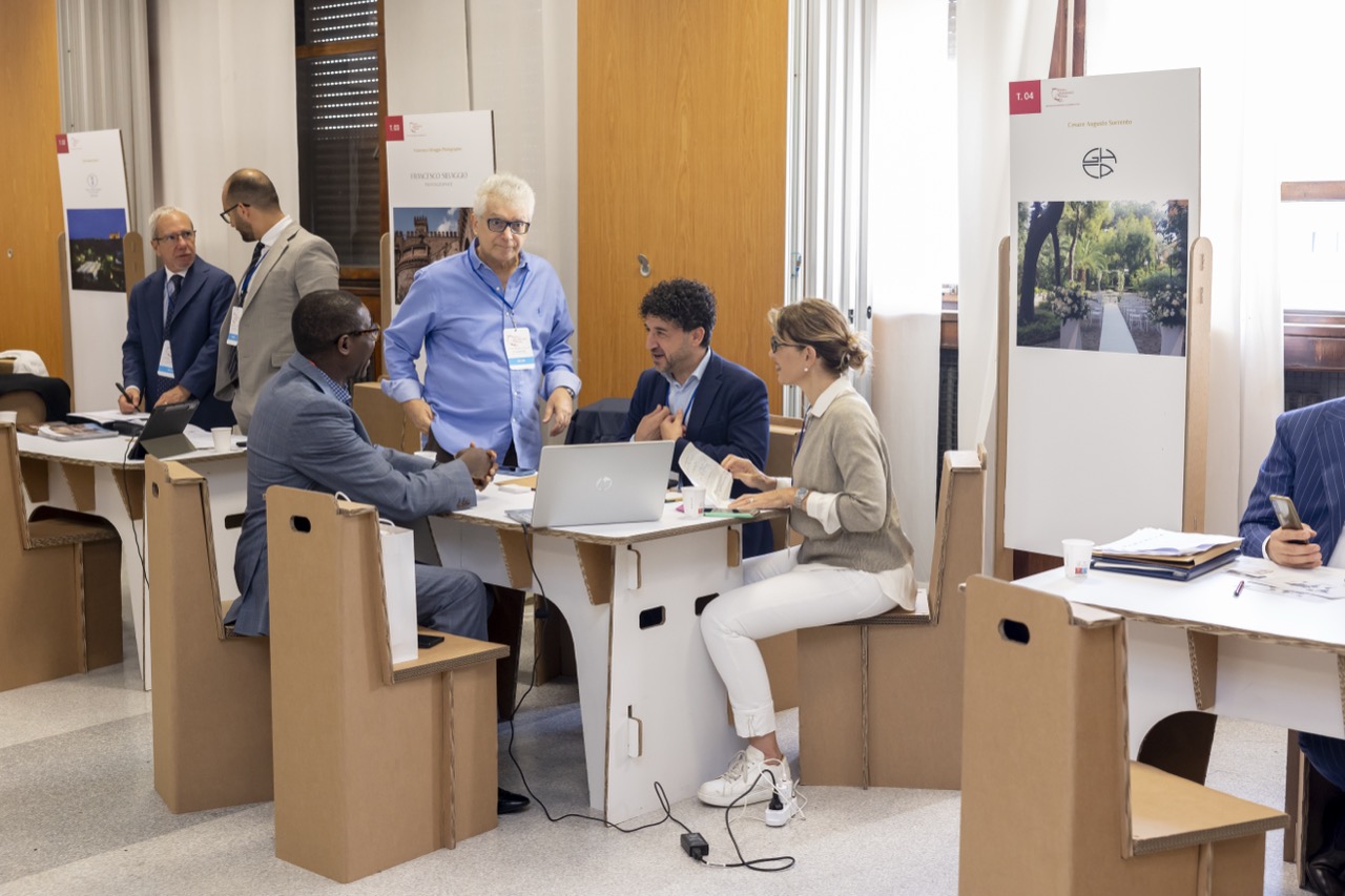 Five participants around a meeting table with a laptop, with display boards behind them