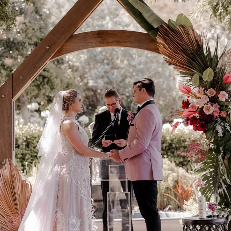 Couple exchanging vows beneath a timber arch, Bona Dea Private Estate